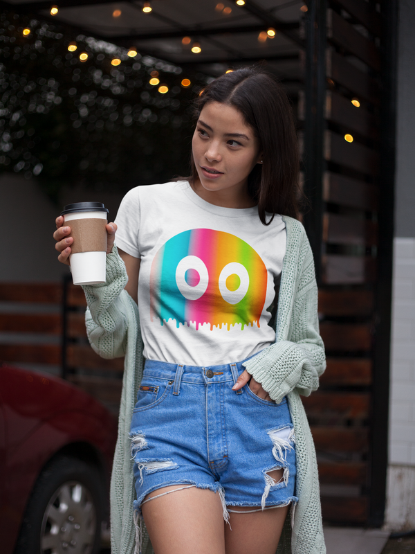 Chica con un café en la mano vistiendo la camiseta blanca de algodón orgánico de Julieta Jaleo fantasma arcoíris